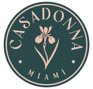 Casadonna Miami logo featuring a pink iris flower on a dark teal circular background with elegant serif lettering.